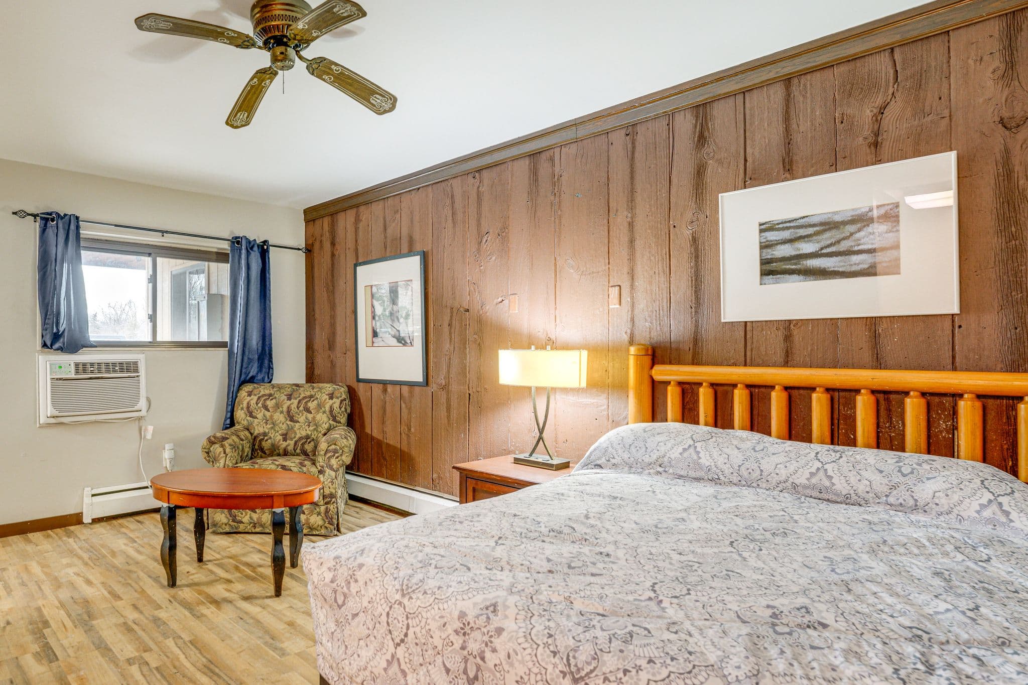 Rustic studio with wood-panel walls and a log-frame bed at The Olde Mill Inn of Clarkston North